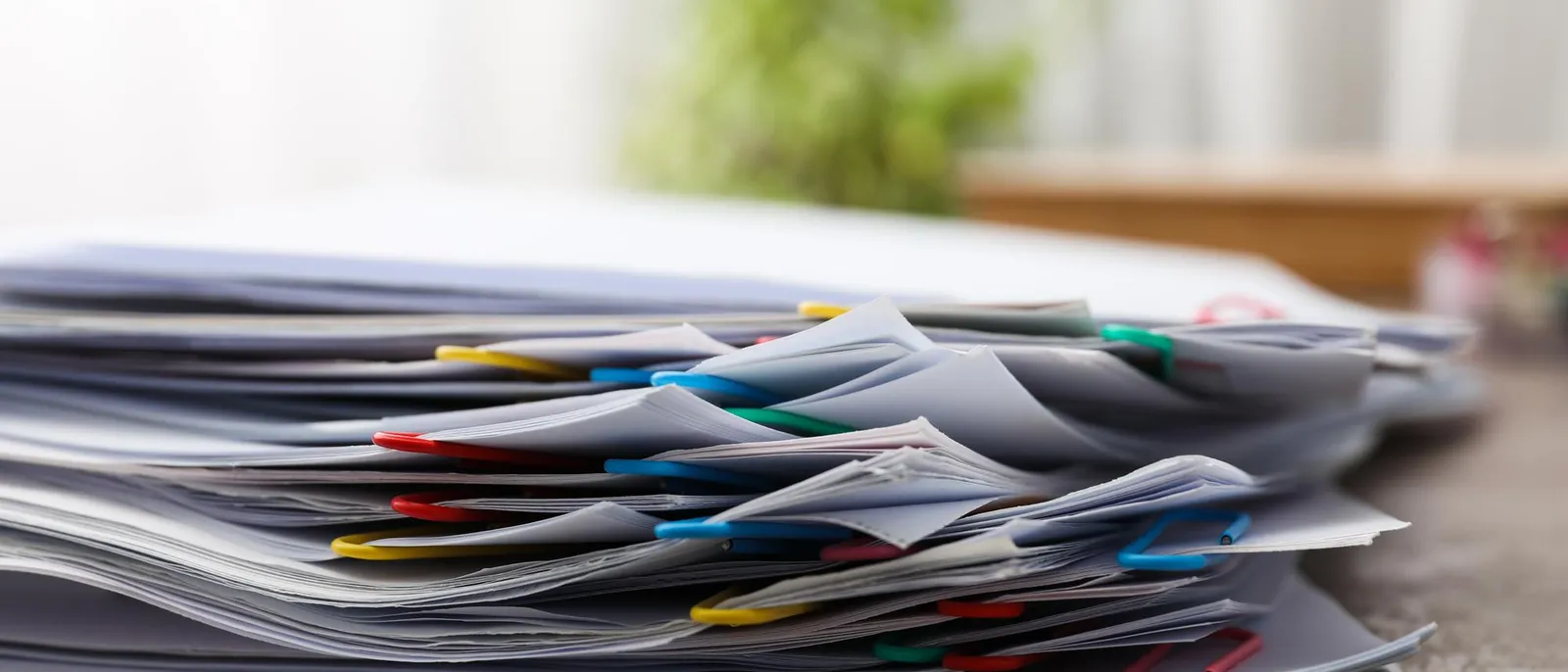 Stack of paper documents with colorful paperclips on a desk