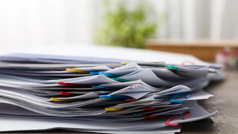 Stack of paper documents with colorful paperclips on a desk